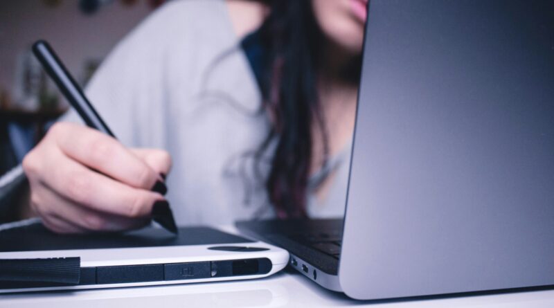 Frau sitzt am Schreibtisch und zeichnet etwas auf dem Tablet